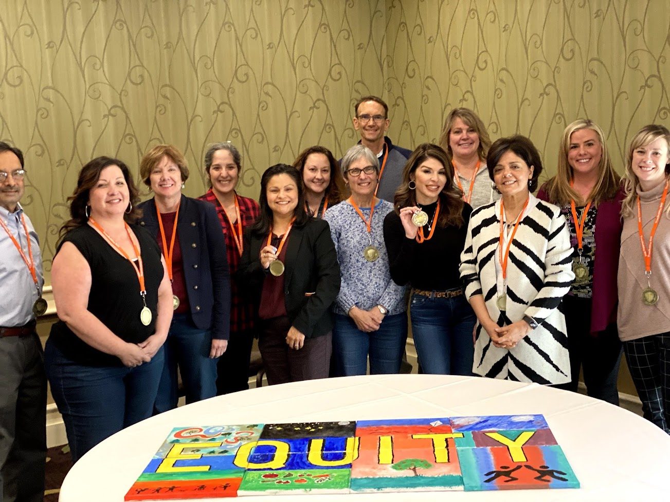 A group celebrating beside their completed Equity mural