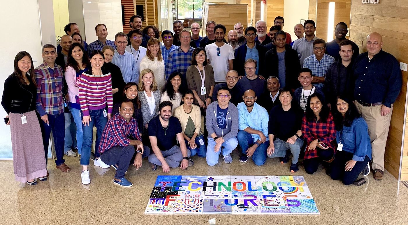 A large team gathered around their colorful finished art