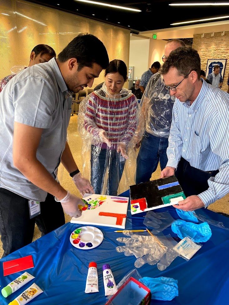 Teammates painting bright artwork together around a table