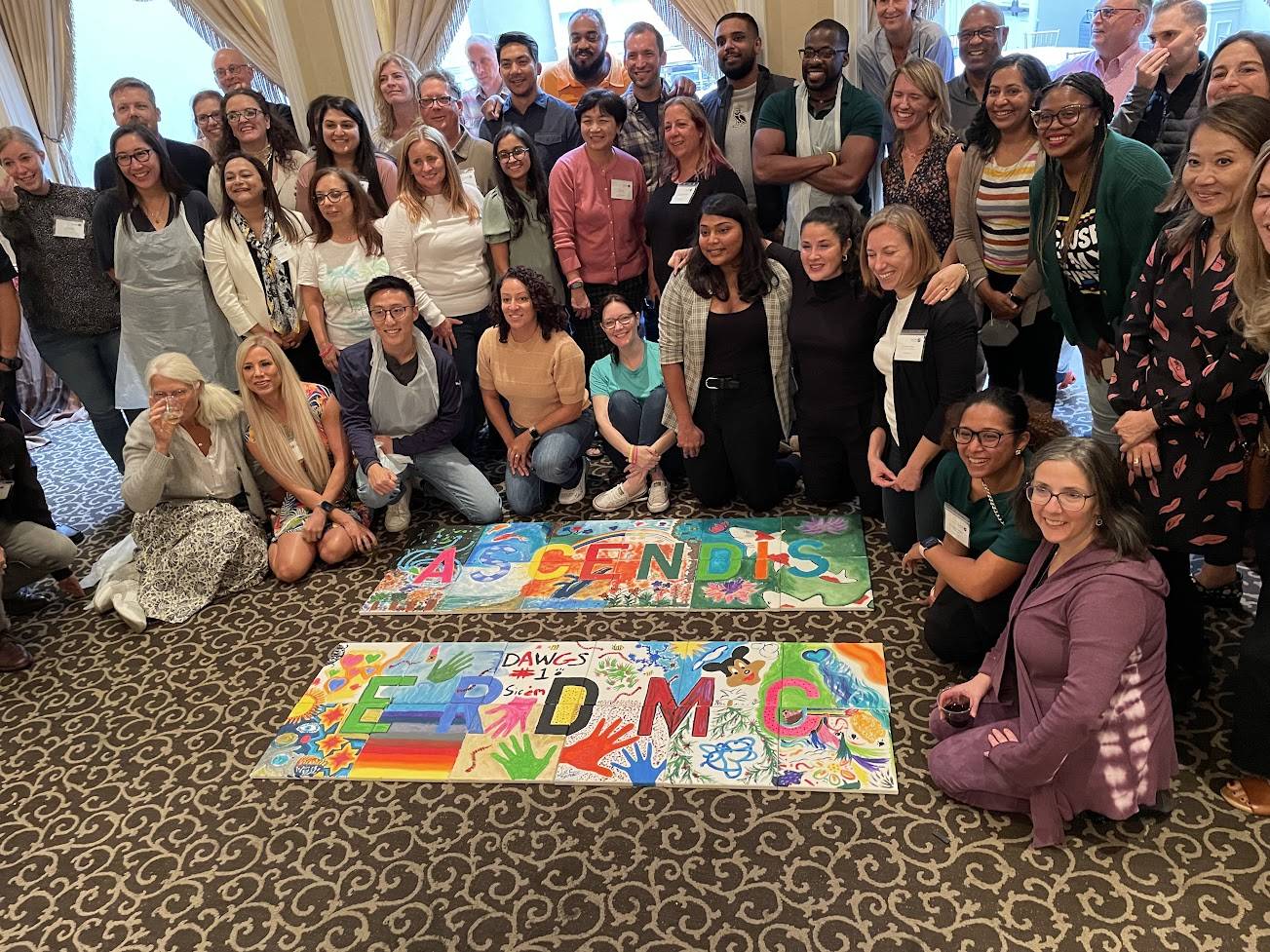 A large group celebrating their completed team mural