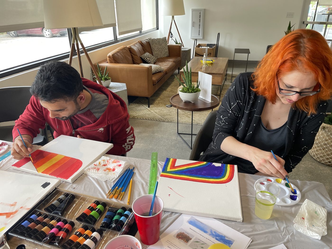 Two artists layering colorful artwork together at their table