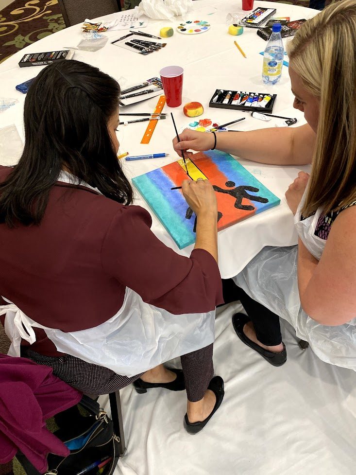 An artist adding detail to a bright blue and orange panel